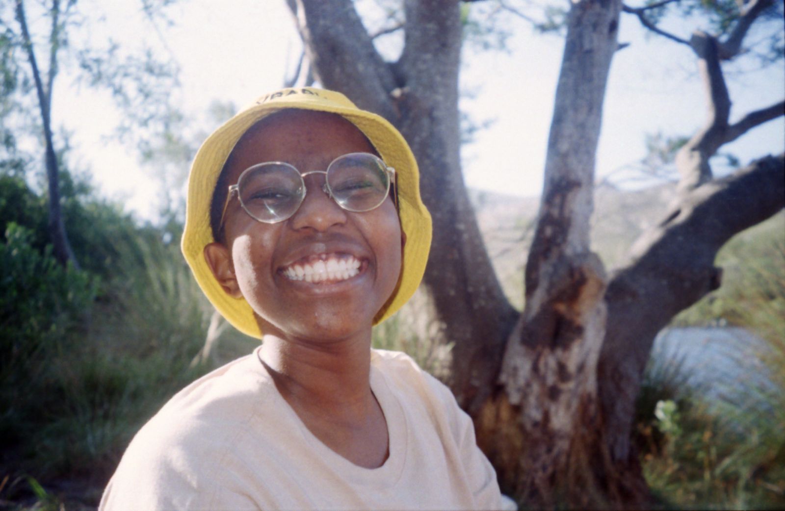 Vuyo smiling widely in front of foresty background.